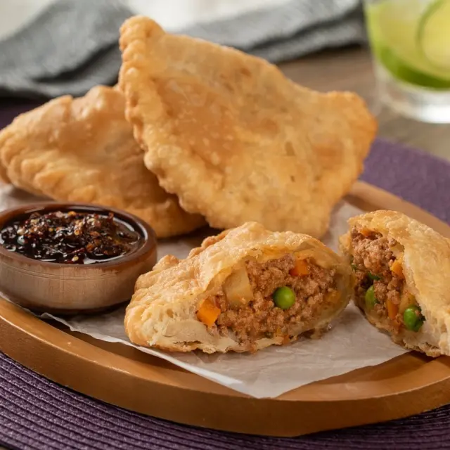 How are empanadas prepared in different parts of the world?