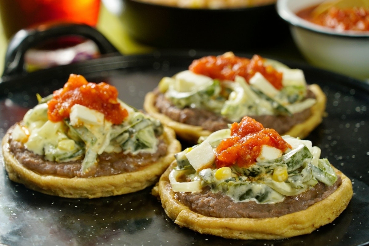 These delicious sopes are slathered with refried beans and topped with raja...